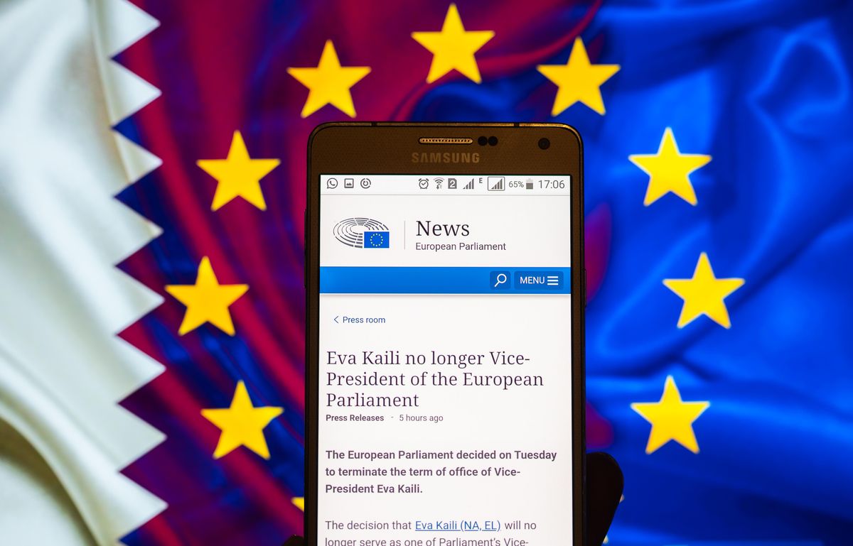 EU & Qatar flags seen behind cellphone screen with press release from the European Parliament.