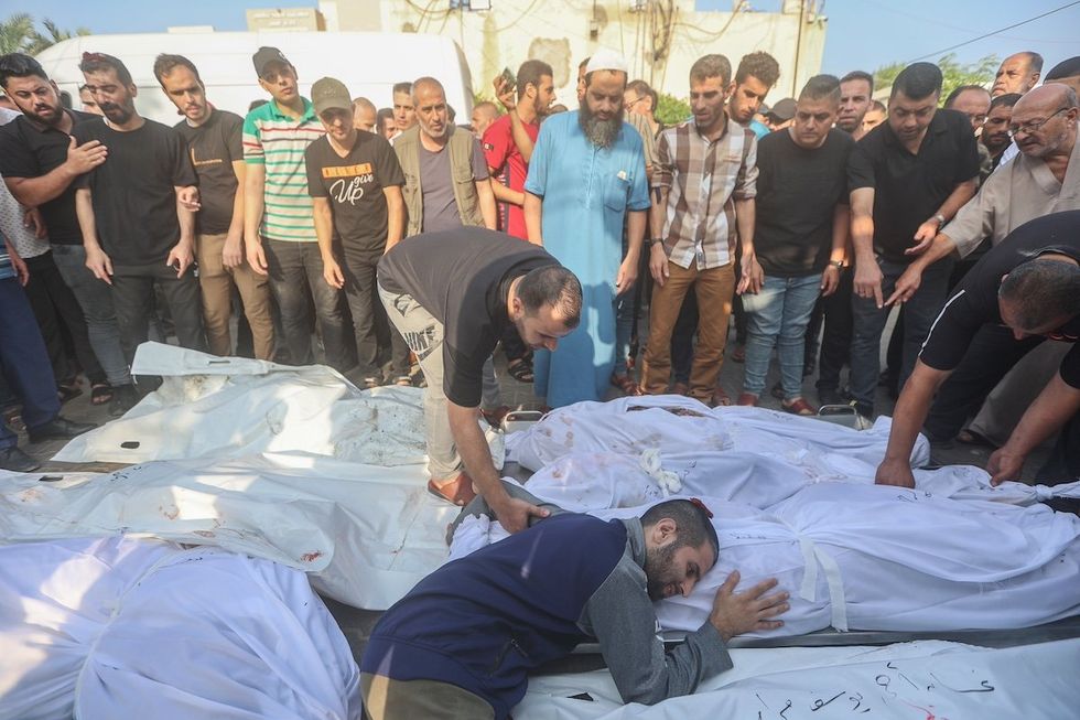 FILE PHOTO: A Palestinian man cries next to bodies of her family members who died following Israeli strikes earlier, during their funeral in Khan Yunis in the southern Gaza Strip.
