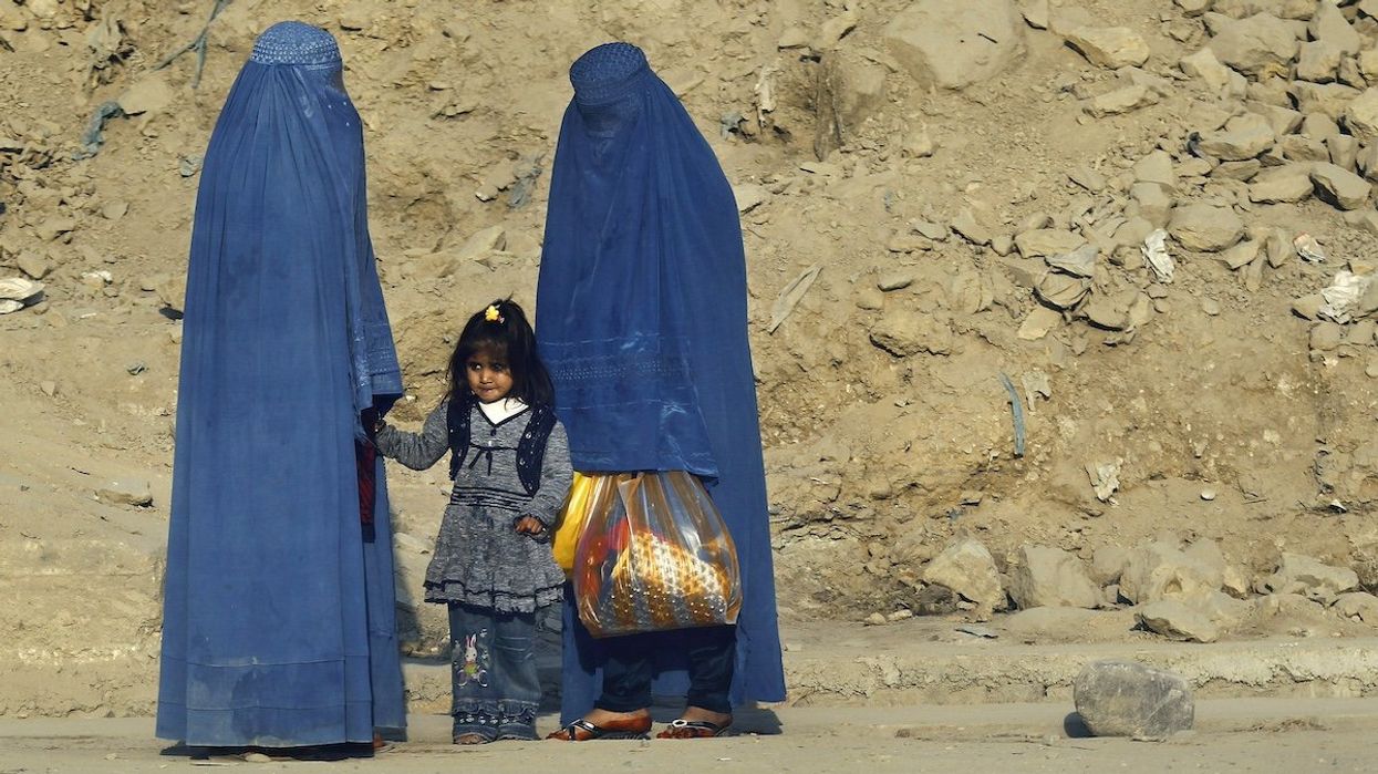 FILE PHOTO: Afghan women clad in burkas wait for transportation on a road in Kabul November 5, 2012.