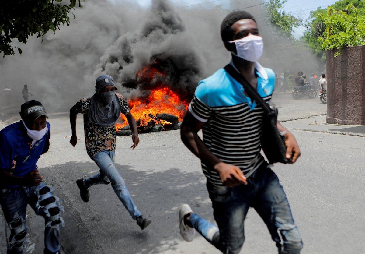 FILE PHOTO: Men run next to burning tires during a protest demanding an end to gang violence, in Port-au-Prince, Haiti, August 14, 2023.