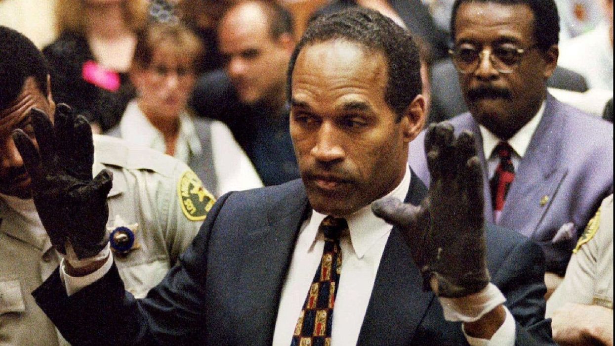 FILE PHOTO: O.J. Simpson, wearing the blood stained gloves found by Los Angeles Police and entered into evidence in Simpson's murder trial, displays his hands to the jury at the request of prosecutor Christopher Darden in this file photograph from June 15, 1995 as his attorney Johnnie Cochran, Jr. (R.) looks on.