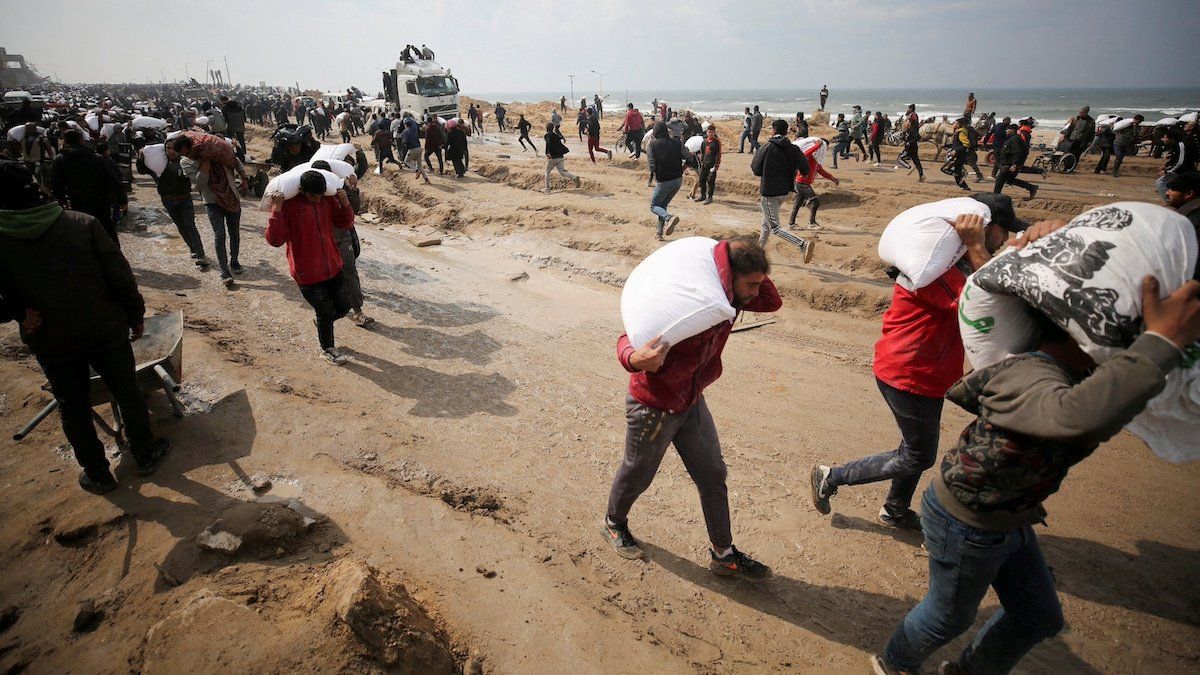 ​FILE PHOTO: Palestinians carry bags of flour they grabbed from an aid truck near an Israeli checkpoint, as Gaza residents face crisis levels of hunger, amid the ongoing conflict between Israel and Hamas, in Gaza City, February 19, 2024. 