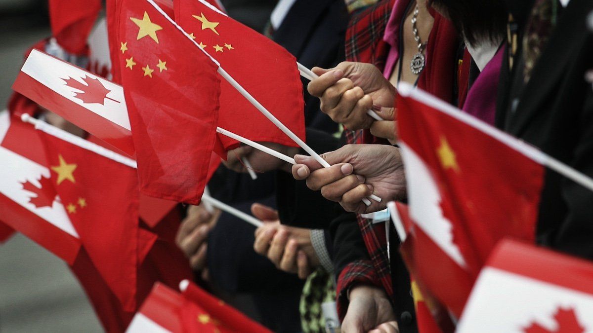 FILE PHOTO: People gather at the airport holding Chinese and Canadian flags while waiting for the arrival of Chinese President Hu Jintao in Vancouver, British Columbia, September 16, 2005.