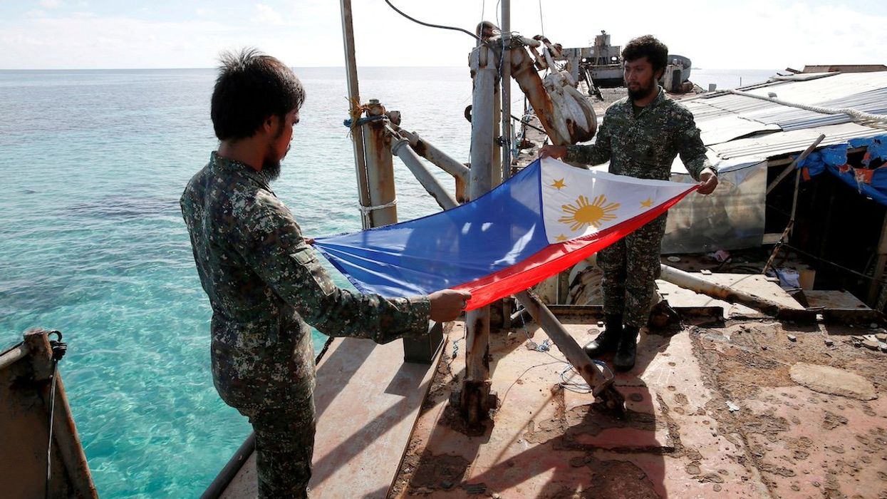 FILE PHOTO: Philippine Marines fold a Philippine national flag during a flag retreat at the BRP Sierra Madre, a marooned transport ship in the disputed Second Thomas Shoal, part of the Spratly Islands in the South China Sea, March 29, 2014.