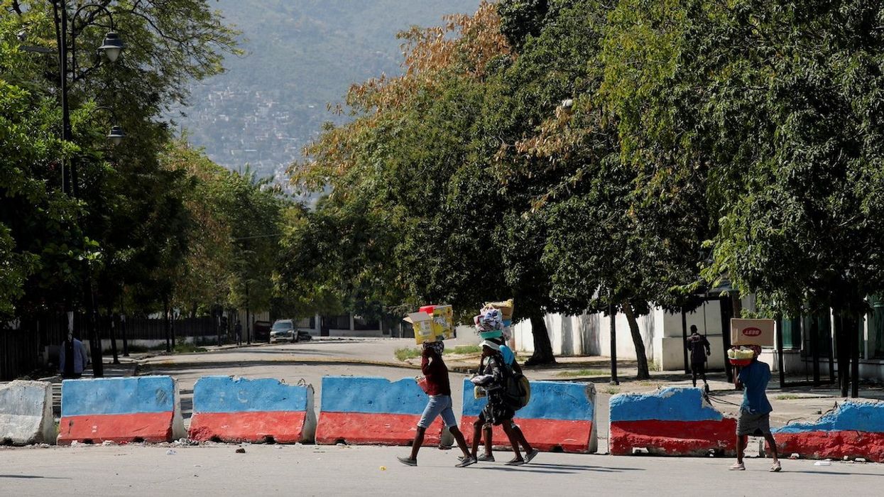 FILE PHOTO: Street vendors carry goods for sale as they walk near the Presidential Palace after Haiti's Prime Minister Ariel Henry pledged to step down following months of escalating gang violence, in Port-au-Prince, Haiti March 12, 2024.