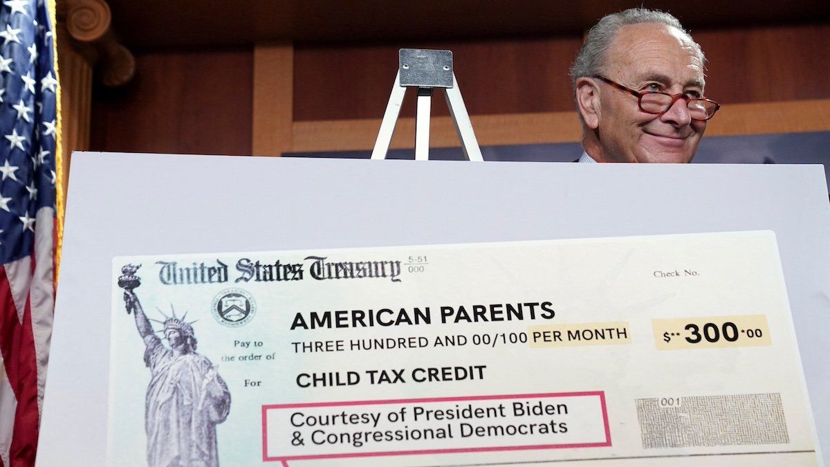FILE PHOTO: U.S. Senate Majority Leader Chuck Schumer smiles from behind a mock U.S. Treasury check as he holds a press conference on the expanded Child Tax Credit payments at the U.S. Capitol in Washington, U.S., July 15, 2021.