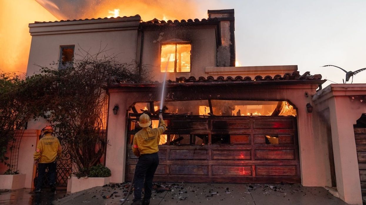 Firefighters attempt to extinguish a fire in a home along the Pacific Coast Highway in the Pacific Palisades neighborhood.