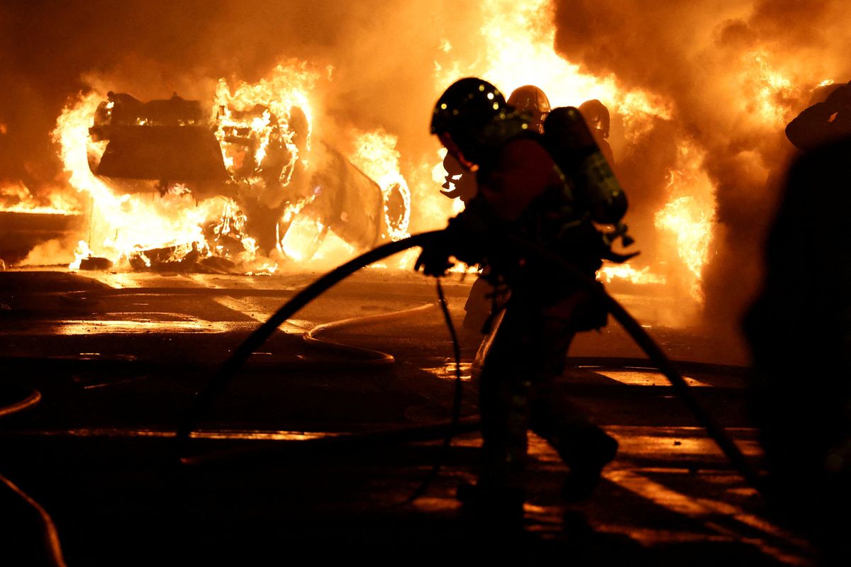 Firefighters extinguish burning vehicles during clashes between protesters and police in Paris, France.