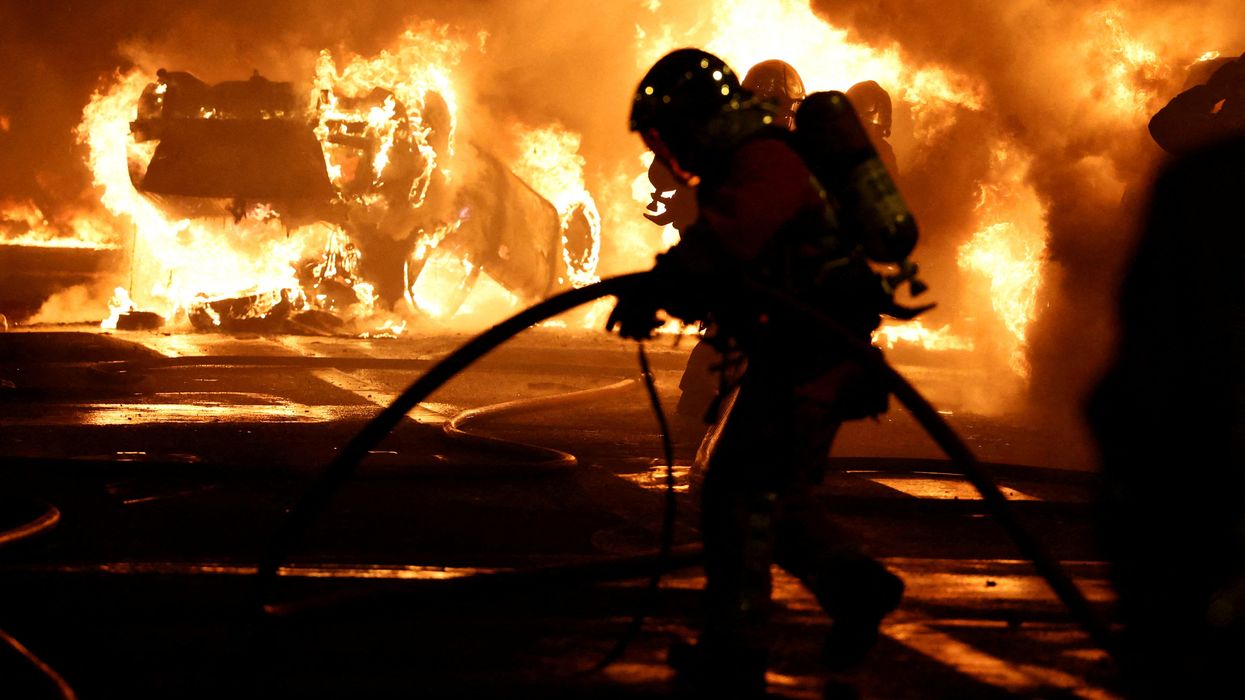 Firefighters extinguish burning vehicles during clashes between protesters and police in Paris, France.