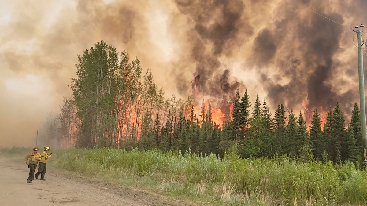 Firefighters retreat as flames approac, amid the Grizzly Wildfire Complex in the East Prairie Metis Settlement, Alberta.