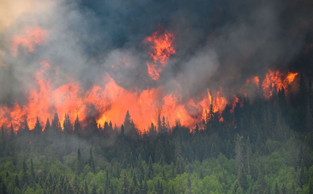 Flames reach upwards along the edge of a wildfire as seen from a Canadian military helicopter near Mistissini, Quebec.