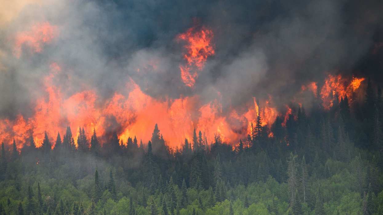 Flames reach upwards along the edge of a wildfire as seen from a Canadian military helicopter near Mistissini, Quebec.