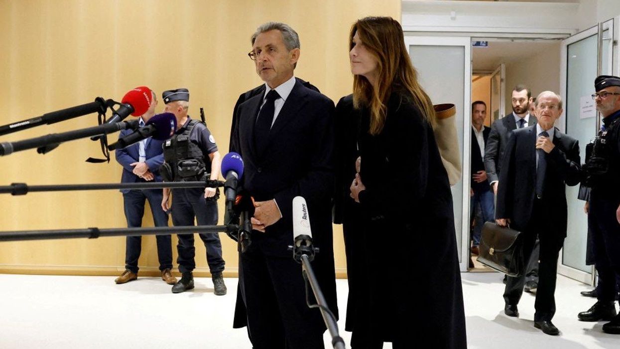 Former French President Nicolas Sarkozy talks to journalists, next to his wife Carla-Bruni Sarkozy and his lawyers, after the verdict in his trial with other defendants on charges of corruption and illegal financing of an election campaign related to alleged Libyan funding of his successful 2007 presidential bid, at the courthouse in Paris, France, September 25, 2025.