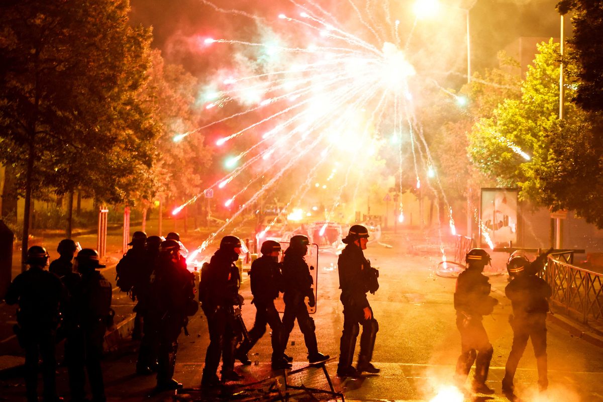 French police stand in position as fireworks go off during clashes with youth in Nanterre, a Paris suburb.
