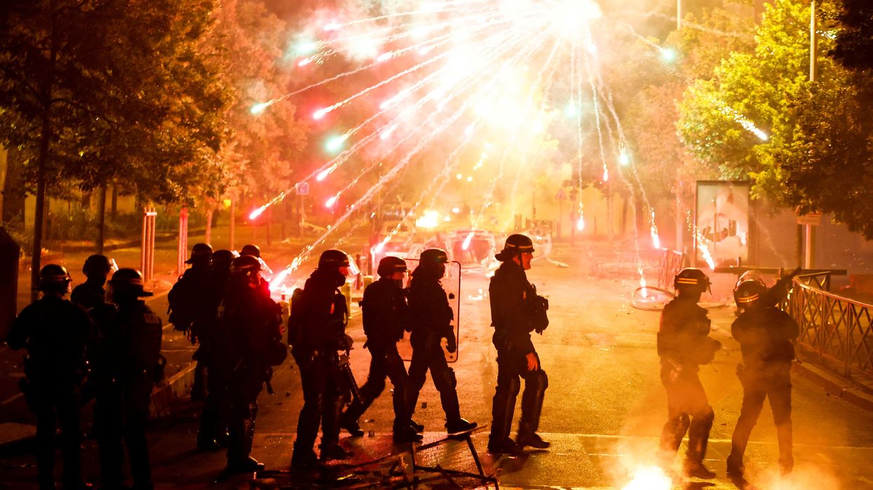 French police stand in position as fireworks go off during clashes with youth in Nanterre, a Paris suburb.