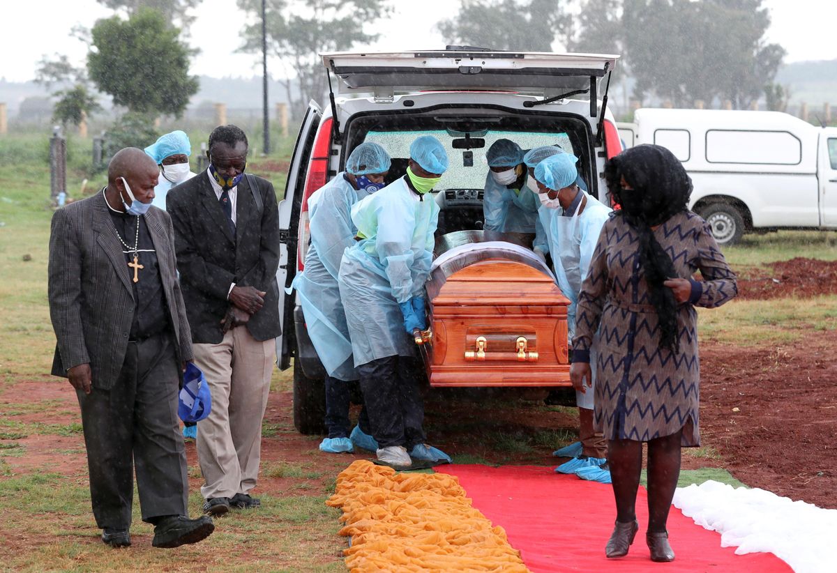 Funeral workers wearing personal protective equipment carry a casket during the burial of a COVID-19 victim, amid a nationwide coronavirus disease (COVID-19) lockdown, at the Olifantsvlei cemetery, south-west of Joburg, South Africa January 6, 2021