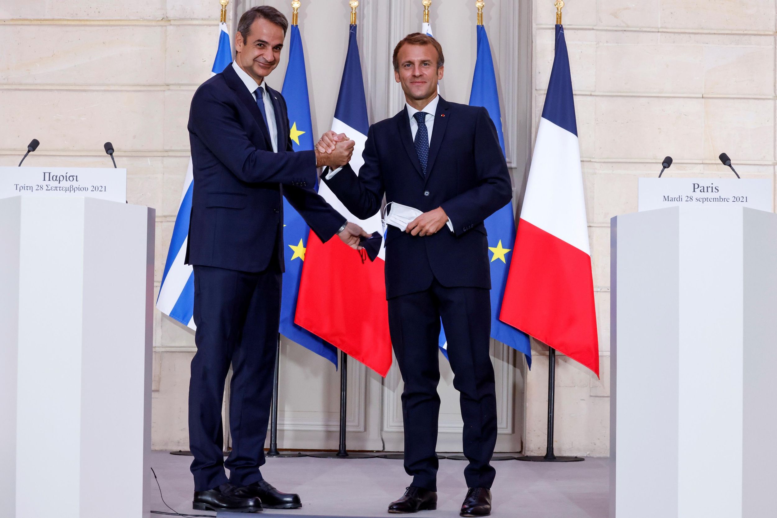 Greek Prime Minister Kyriakos Mitsotakis speaks as French President Emmanuel Macron listens on during a signing ceremony of a new defence deal at The Elysee Palace in Paris, France September 28, 2021. 