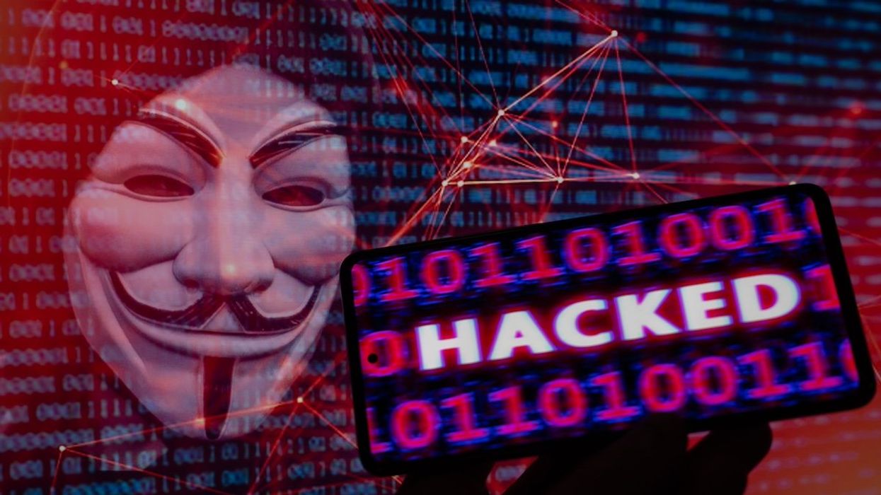 Hacked displayed on a mobile with binary code with in the background Anonymous mask. On 9 August 2023 in Brussels, Belgium.