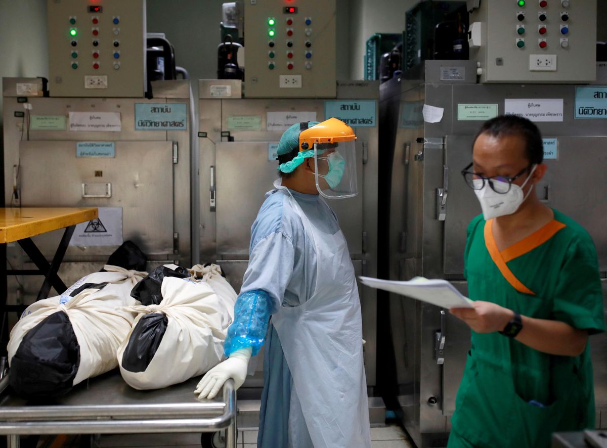 Health care workers stand near dead bodies prior moving them to a container, after a hospital morgue overwhelmed by COVID-19 deaths begun to store bodies in refrigerated containers, as the country struggles to deal with its biggest outbreak to date, in Pathum Thani, Thailand July 31, 2021