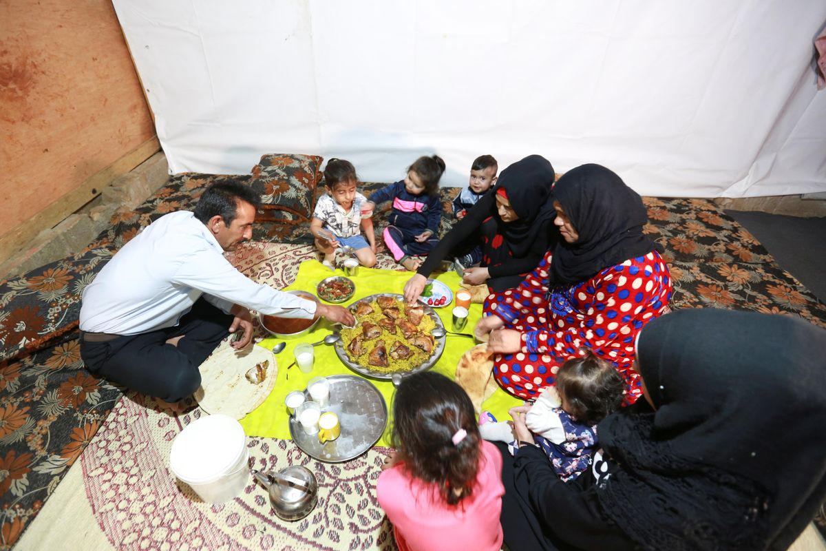 Hussein al-Khaled and his family eat their Iftar (breaking fast) meal during the holy month of Ramadan inside a tent at an informal tented settlement in Bar Elias, in the Bekaa Valley, Lebanon April 22, 2021.