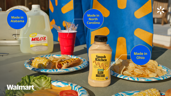Image of a picnic table with Dijon mustard, chips, salad, hotdog, and corn