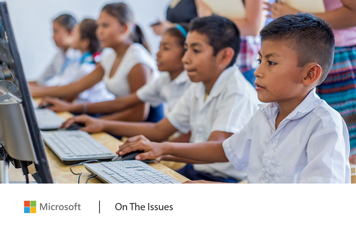Image of a row of schoolchildren (boys and girls in white collared shirts) sitting in front of desktop computers and keyboards, with their hands on computer mouses