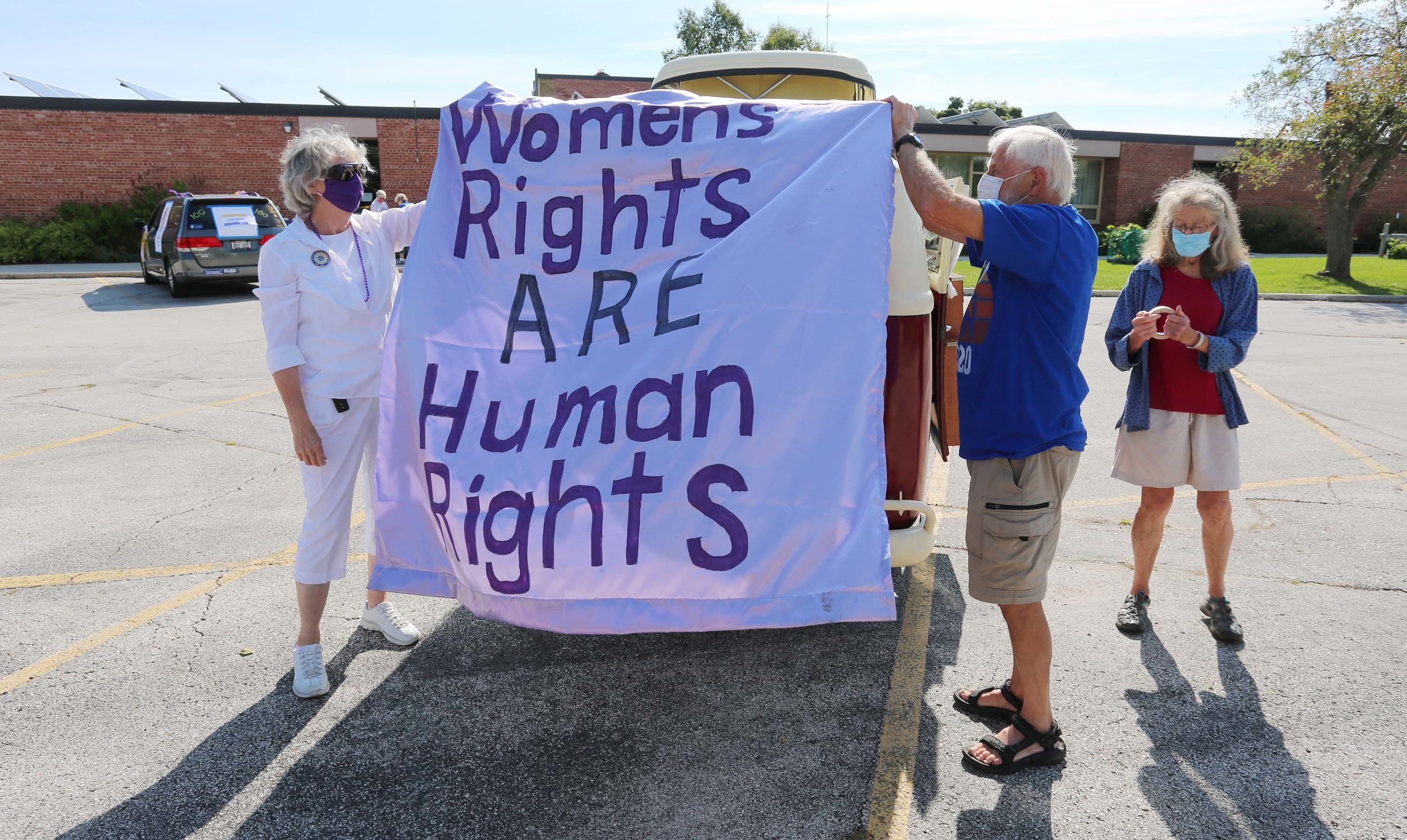 Mary Koczan, left, and Dennis Arnott, with his wife Jane, work on decorating, Saturday, August 22, 2020, in Sheboygan, Wis., Arnott's 1967 VW bus before a parade celebrating the 100th anniversary of the passing of the 19th Amendment, which gave women the right to vote