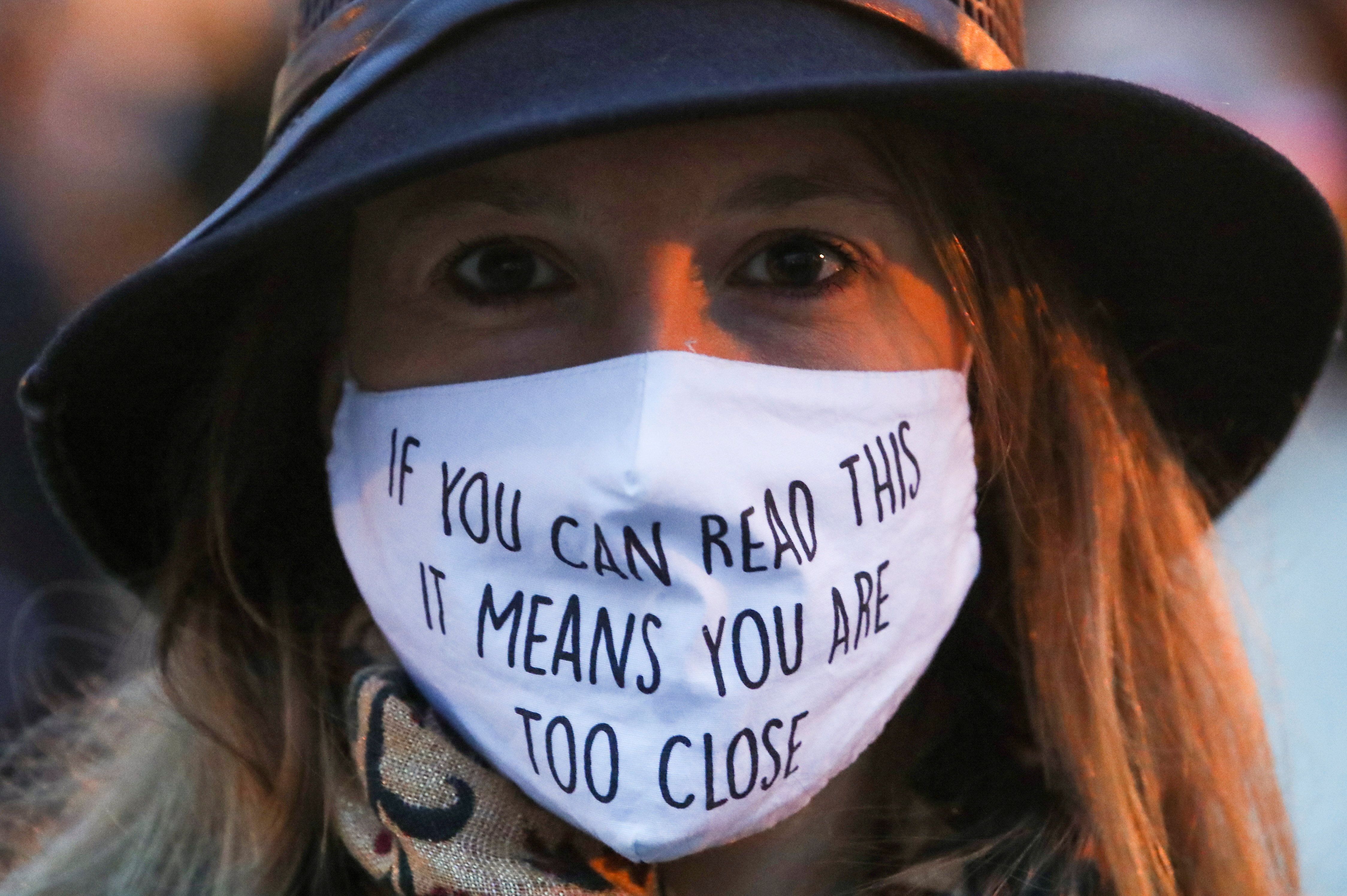 A woman wearing a face mask that says, "if you can read this it means you are too close."