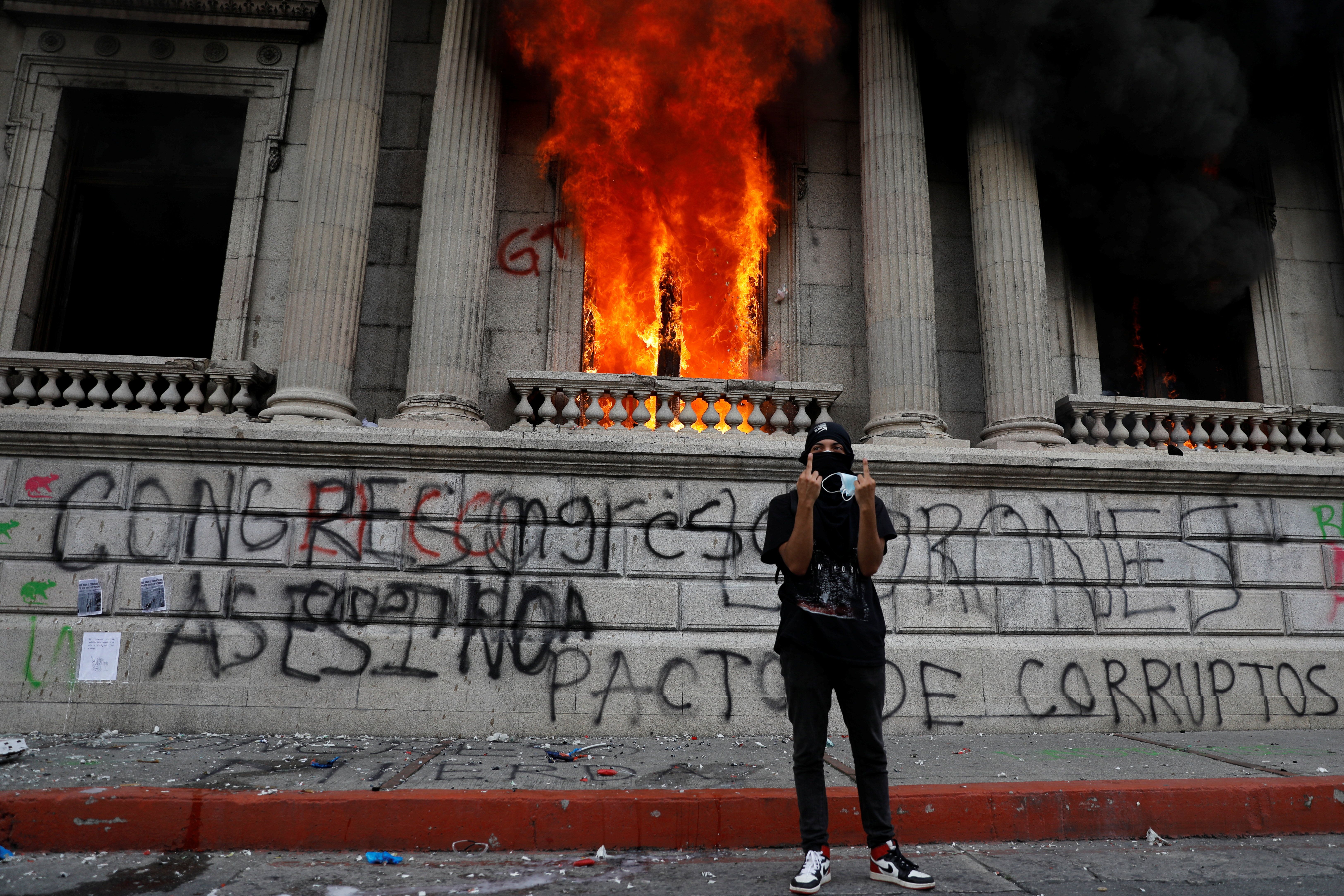 A demonstrator gestures after demonstrators set an office of the Congress building on fire during a protest demanding the resignation of President Alejandro Giammattei, in Guatemala City, Guatemala November 21, 2020.