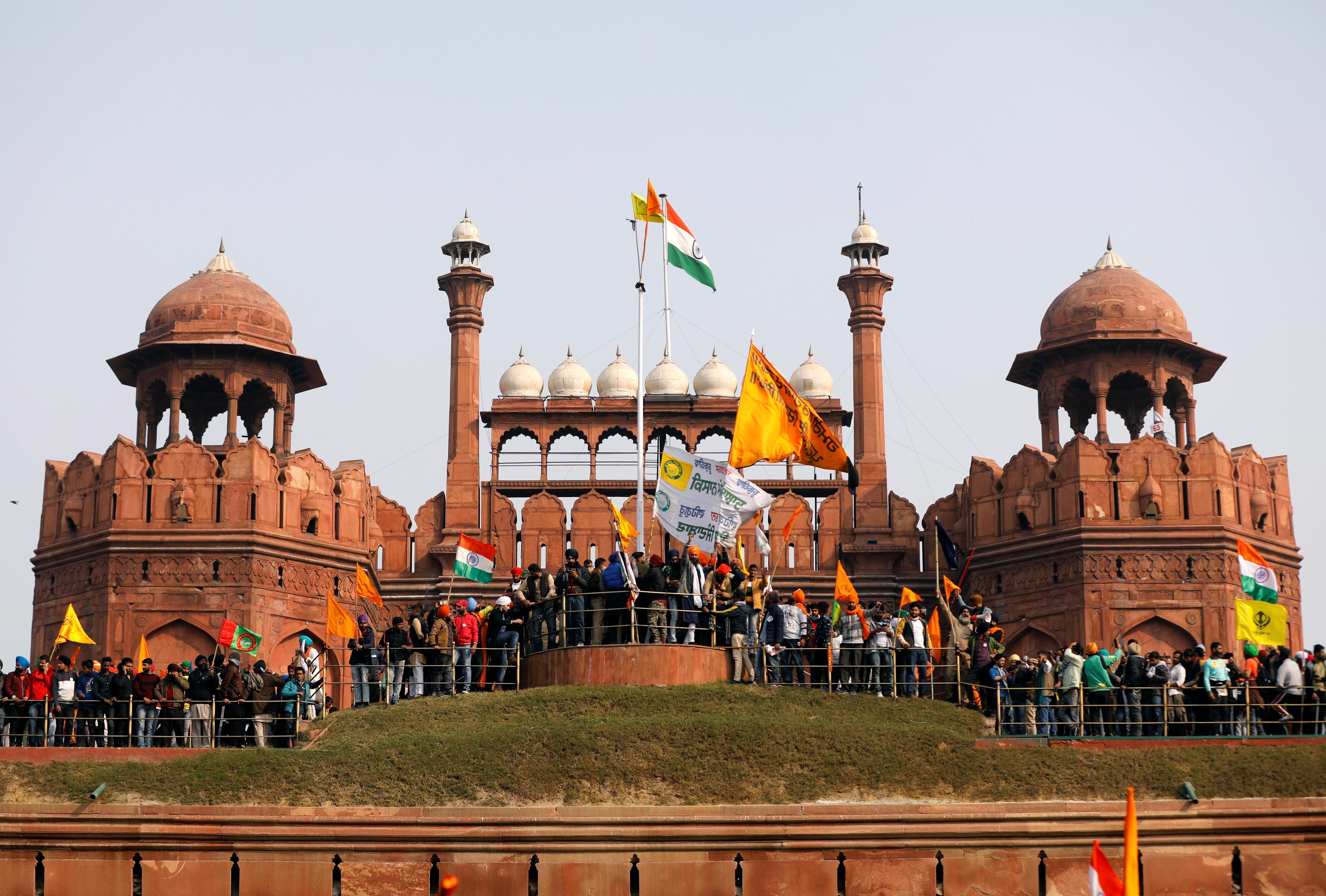 Indian farmers wave flags during a protest against farm laws introduced by the government at the historic Red Fort in Delhi. REUTERS/Adnan Abidi