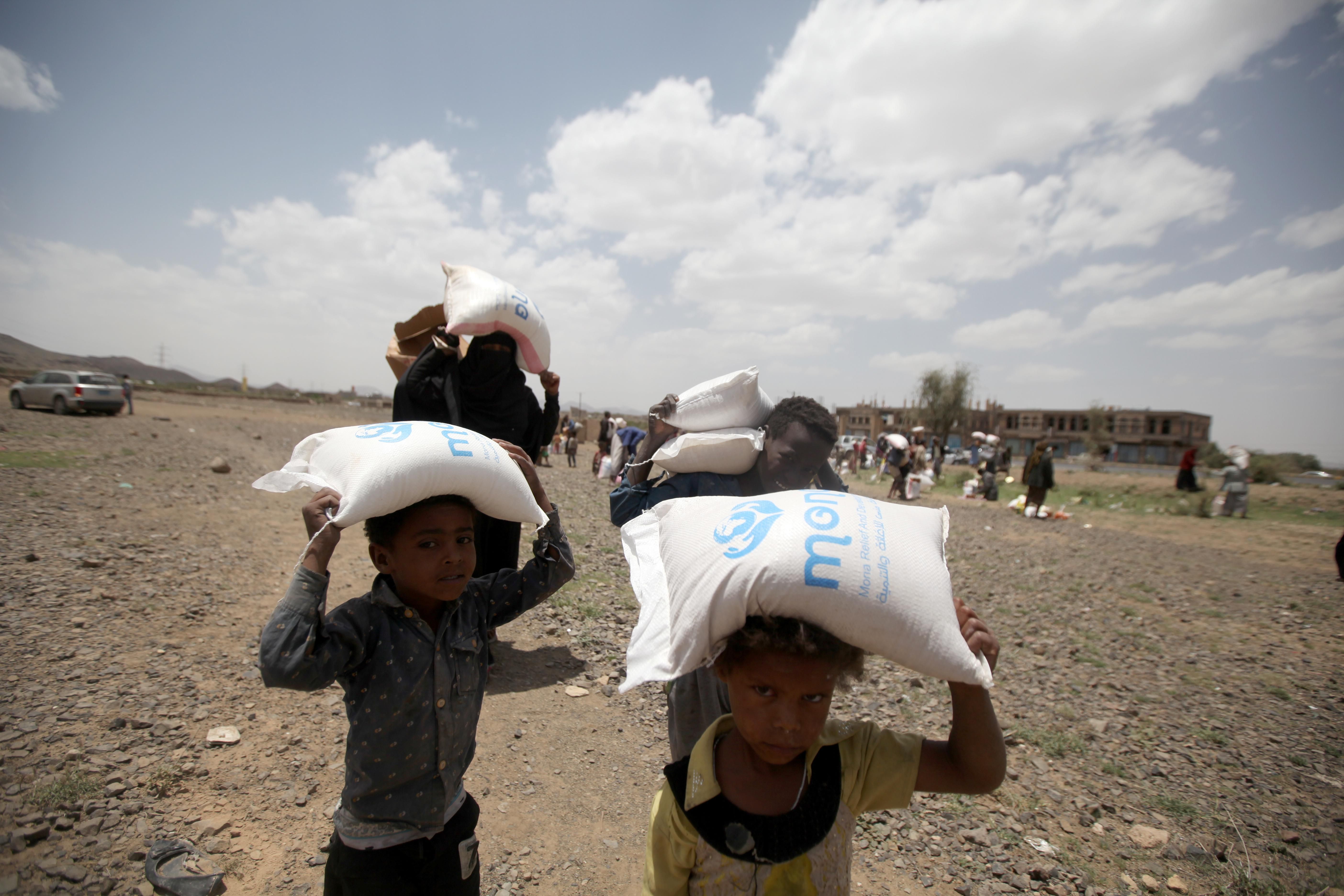 People carry food aid they received on the outskirts of Sanaa, Yemen.