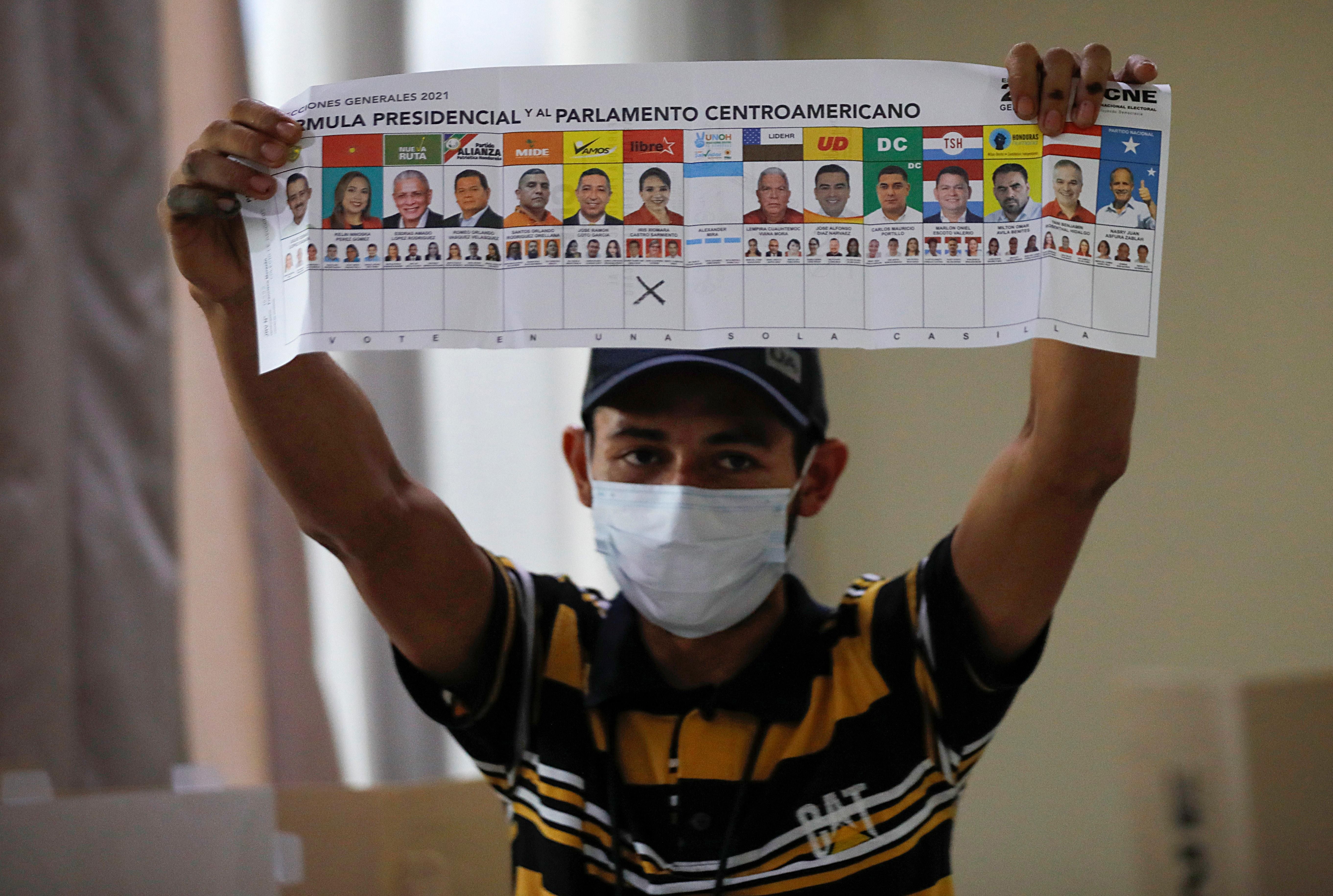 An election volunteer displays the ballot as vote counting begins during the general election, at a school in Catacamas, Honduras, November 28, 2021.