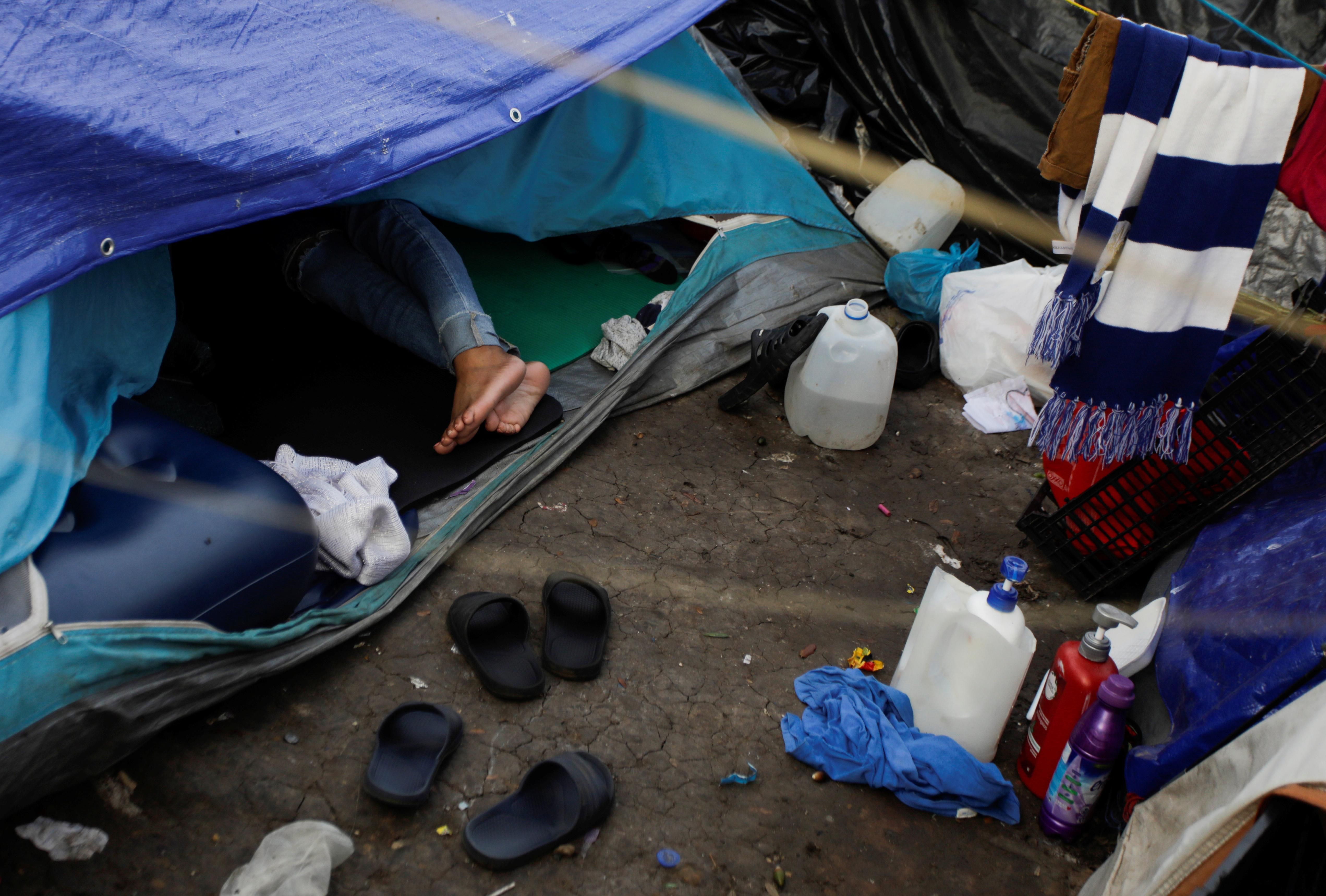 A migrant woman seeking asylum in the U.S. rests inside a tent as she waits for her request to be processed, at a migrant encampment set in a public square in Reynosa, Mexico December 3, 2021.