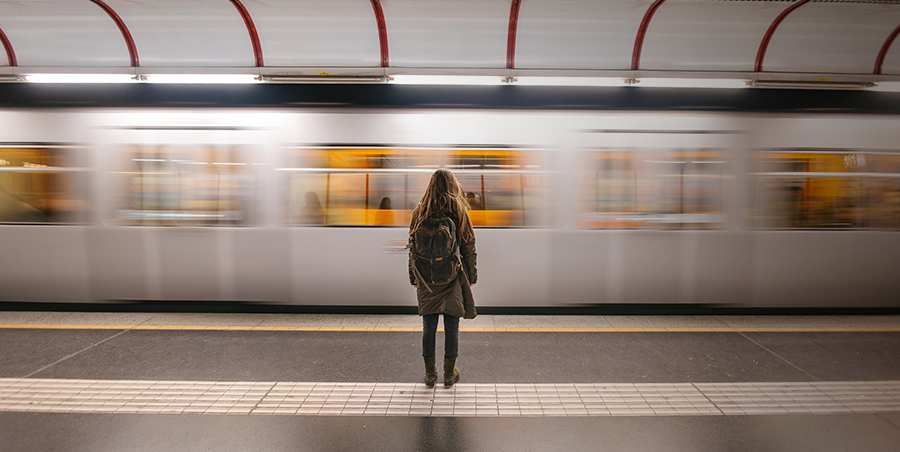 Woman at the train station as a train zooms past her