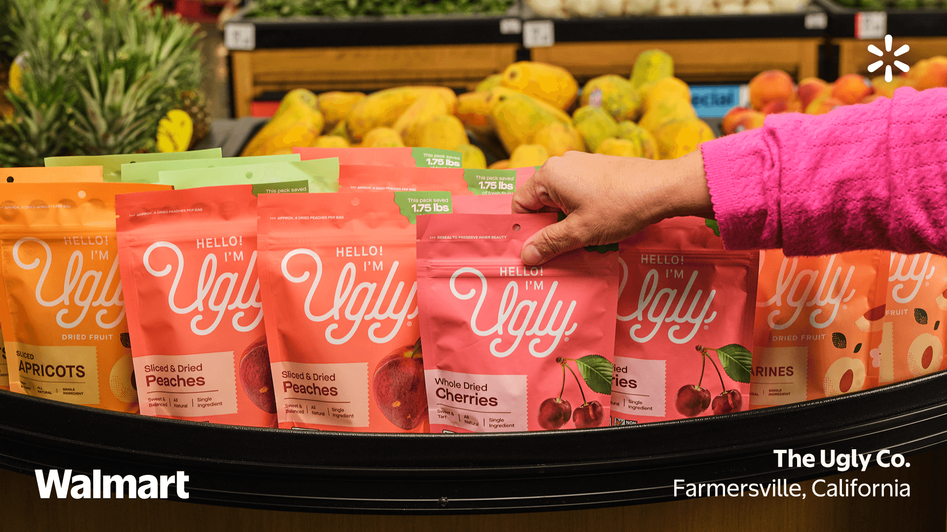 Person picking up packets of Hello I'm Ugly dried fruits at a store