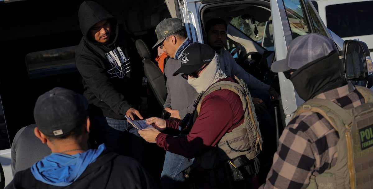 Immigration and Customs Enforcement (ICE) agents check the identity documents of a group of agricultural workers at a grocery store parking lot during an immigration raid in Mecca, California, U.S. December 19, 2025. 