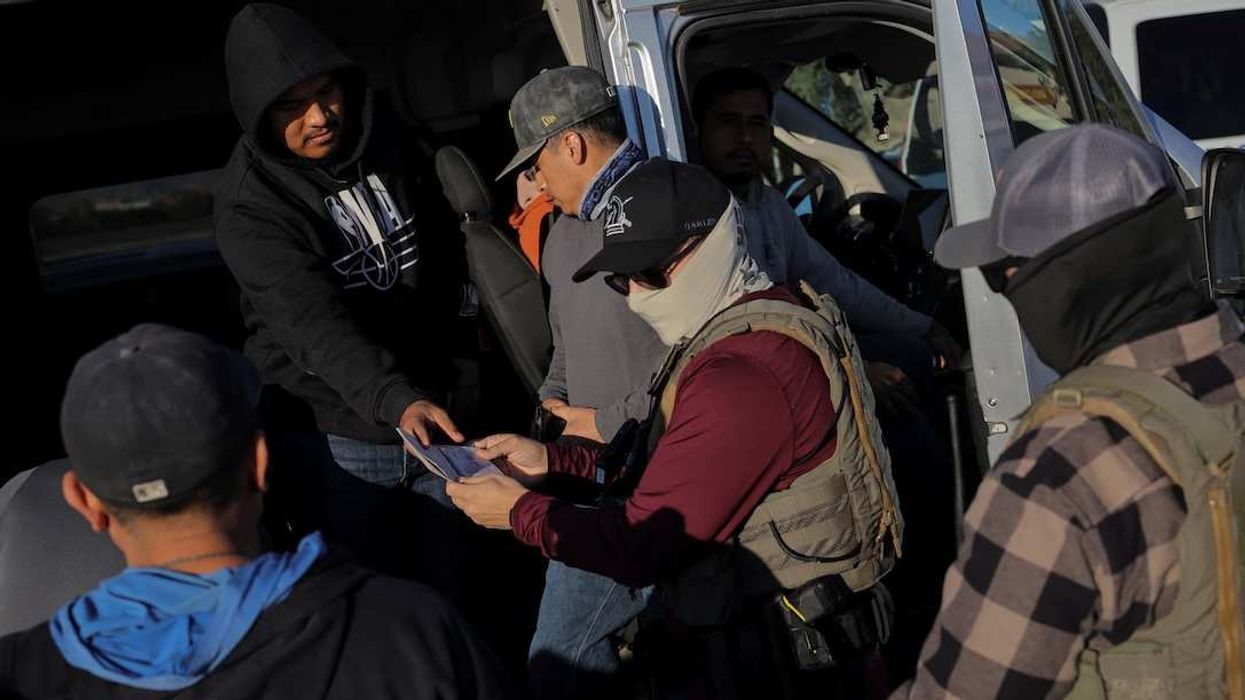 Immigration and Customs Enforcement (ICE) agents check the identity documents of a group of agricultural workers at a grocery store parking lot during an immigration raid in Mecca, California, U.S. December 19, 2025.
