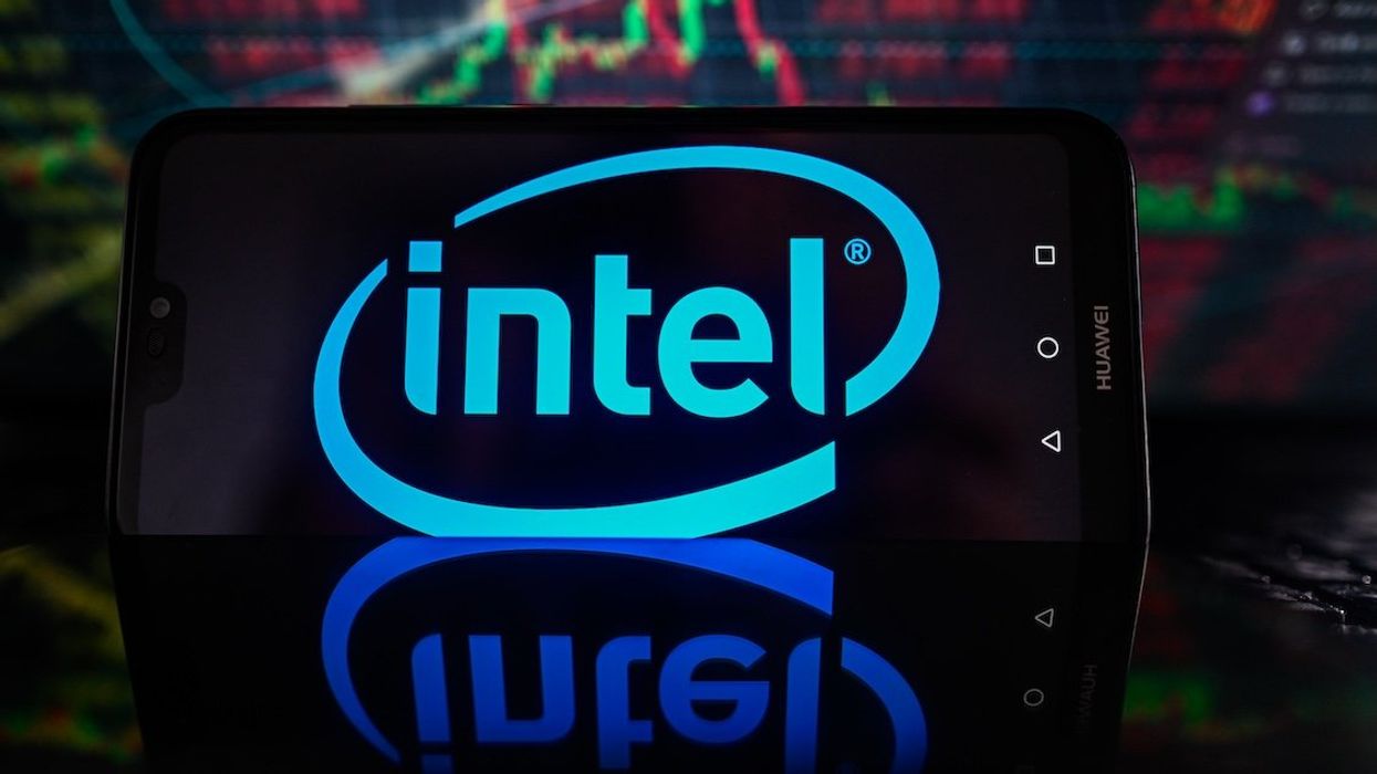 In this photo illustration, Intel logo is displayed on a smartphone with stock market percentages on the background.