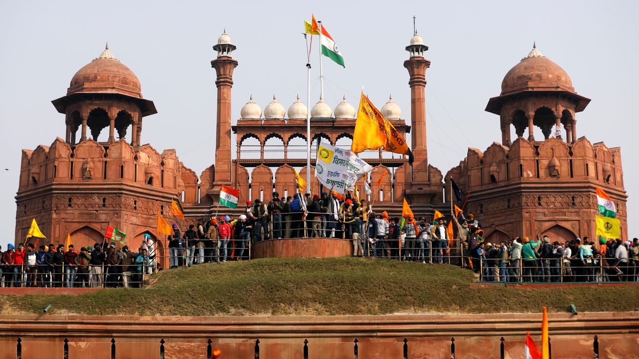 Indian farmers wave flags during a protest against farm laws introduced by the government at the historic Red Fort in Delhi. REUTERS/Adnan Abidi