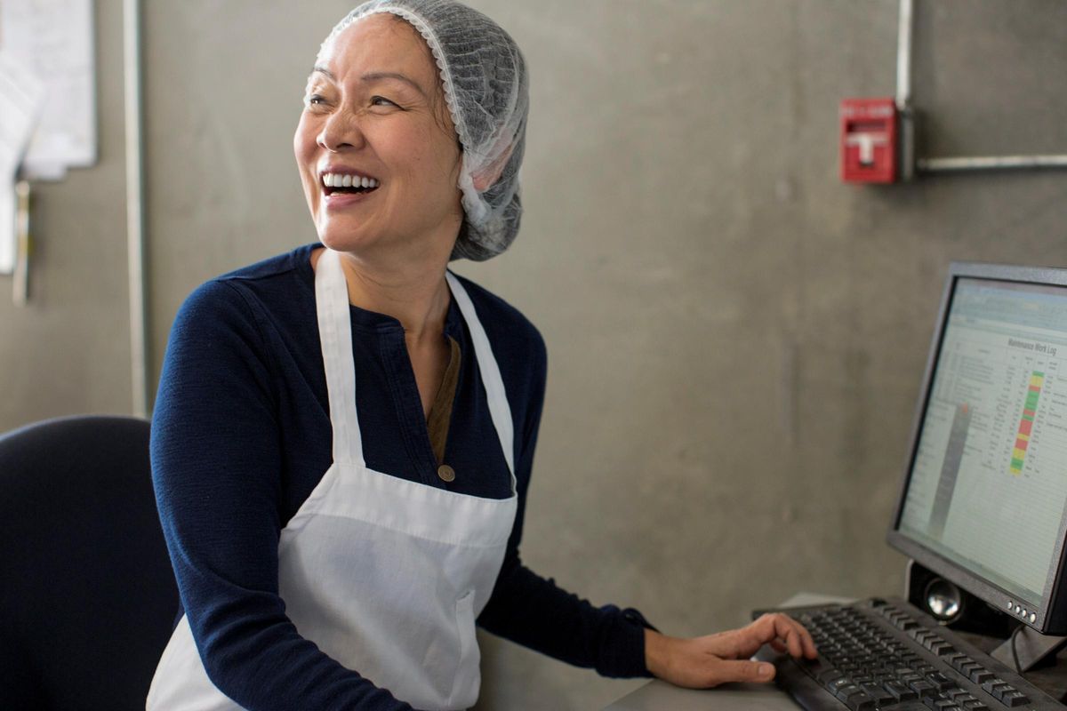 Indo-Pacific woman smiling while she uses her computer.