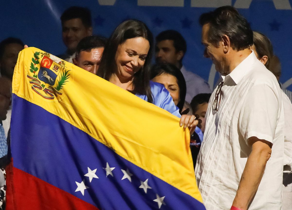 Industrial engineer and former lawmaker Maria Corina Machado holds up a Venezuelan flag as she reacts to the vote count after Venezuelans voted in a primary to choose a unity opposition candidate to face Venezuela's President Nicolas Maduro in his probable re-election bid in 2024, in Caracas, Venezuela October 23, 2023.