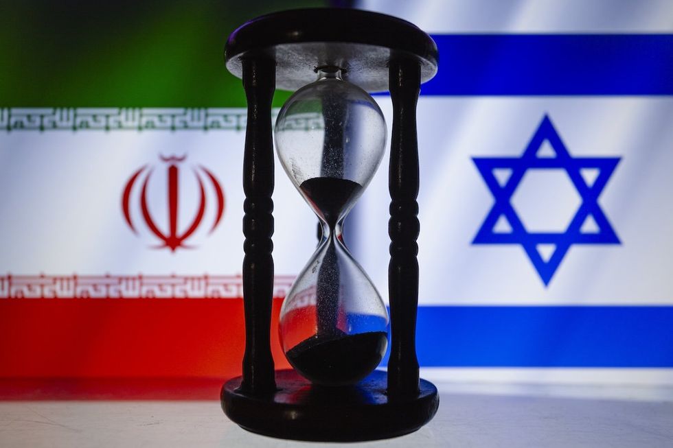 Iranian and Israeli flags behind an hourglass.