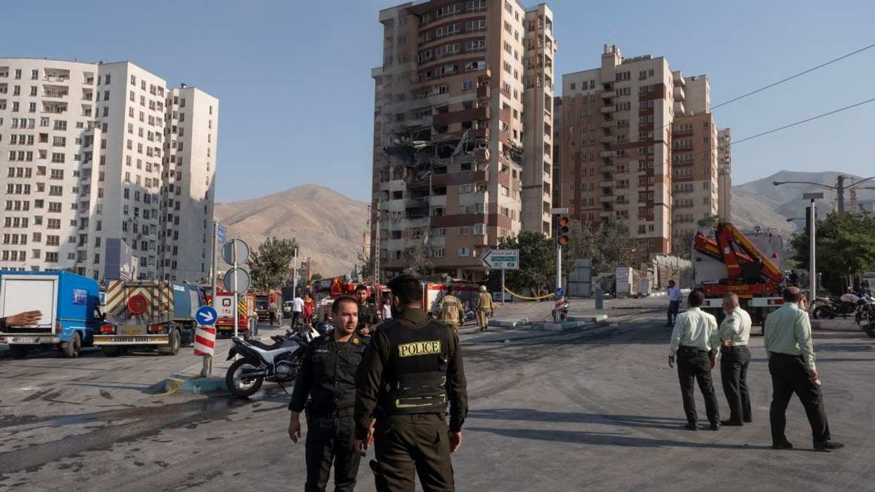 Iranian policemen monitor an area near a residential complex that is damaged in Israeli attacks in Tehran, Iran, on June 13, 2025.