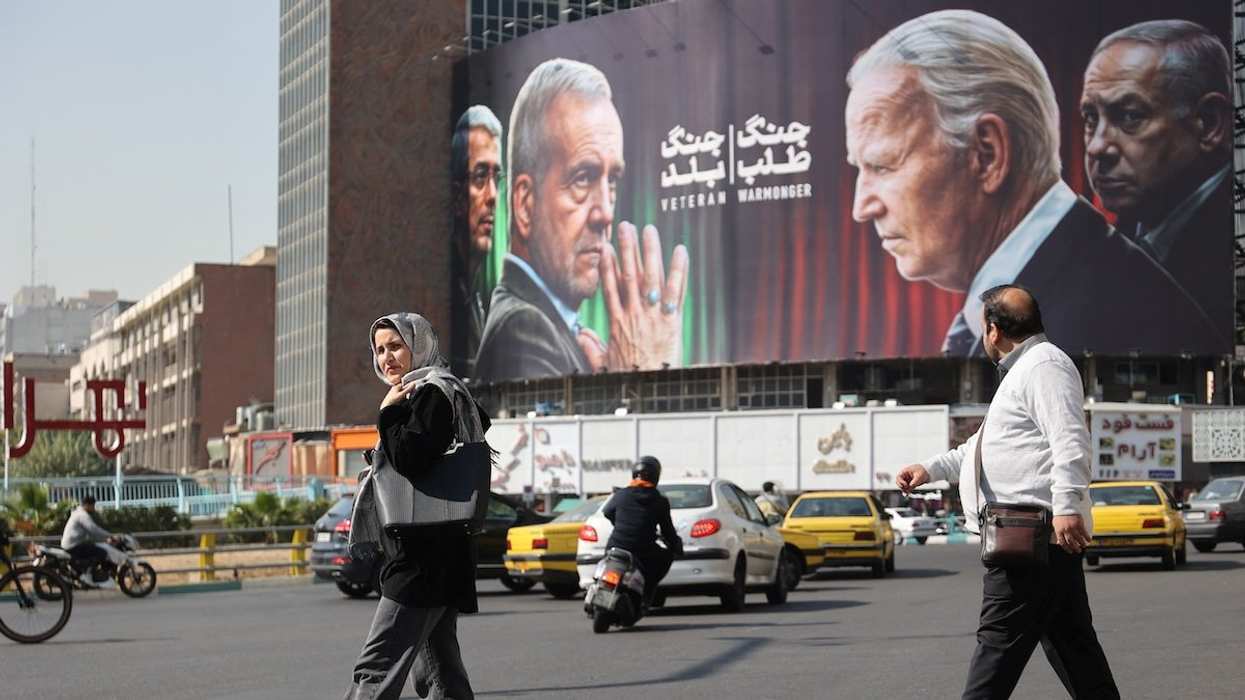 Iranians walk next to an anti-US and Israeli billboard with pictures of Iranian President Masoud Pezeshkian and Iranian Armed Forces Chief of Staff, Major General Mohammad Bagheri, and US President Joe Biden and Israeli Prime Minister Benjamin Netanyahu, on a street in Tehran, Iran, October 27, 2024.