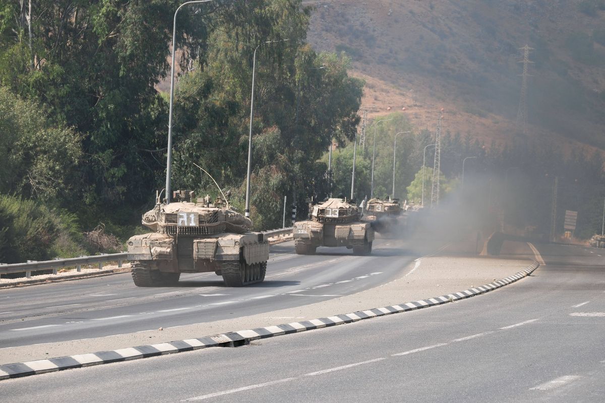 Israeli Merkava tanks roll on a road on the outskirts of the northern town of Kiryat Shmona near the border with Lebanon on October 8, 2023. Lebanon s Hezbollah and Israel said they traded cross-border fire on October 8, as Israel fought the Shiite movement s ally Hamas on its southern flank a day after militants from the Palestinian group stormed its Gaza frontier.