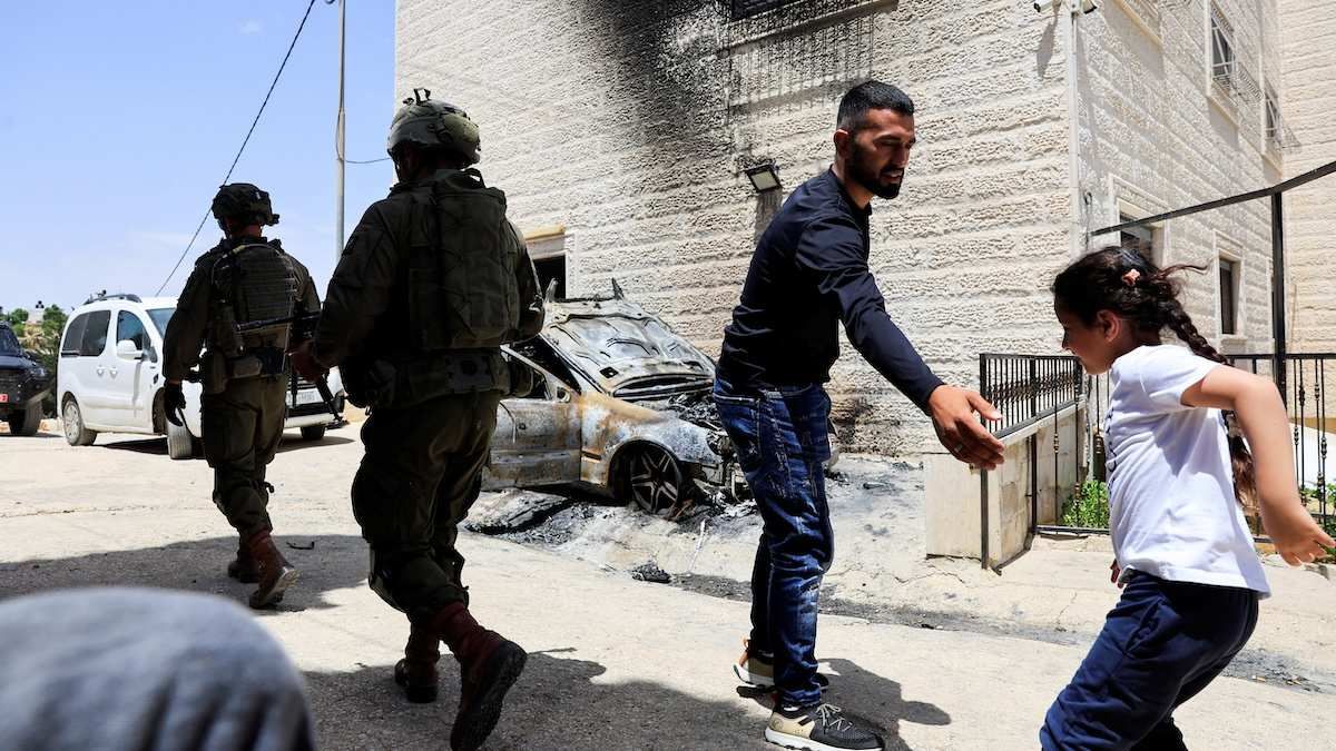 ​Israeli soldiers walk near a damaged car in Halhul, near Hebron, in the Israeli-occupied West Bank, on May 20, 2026.