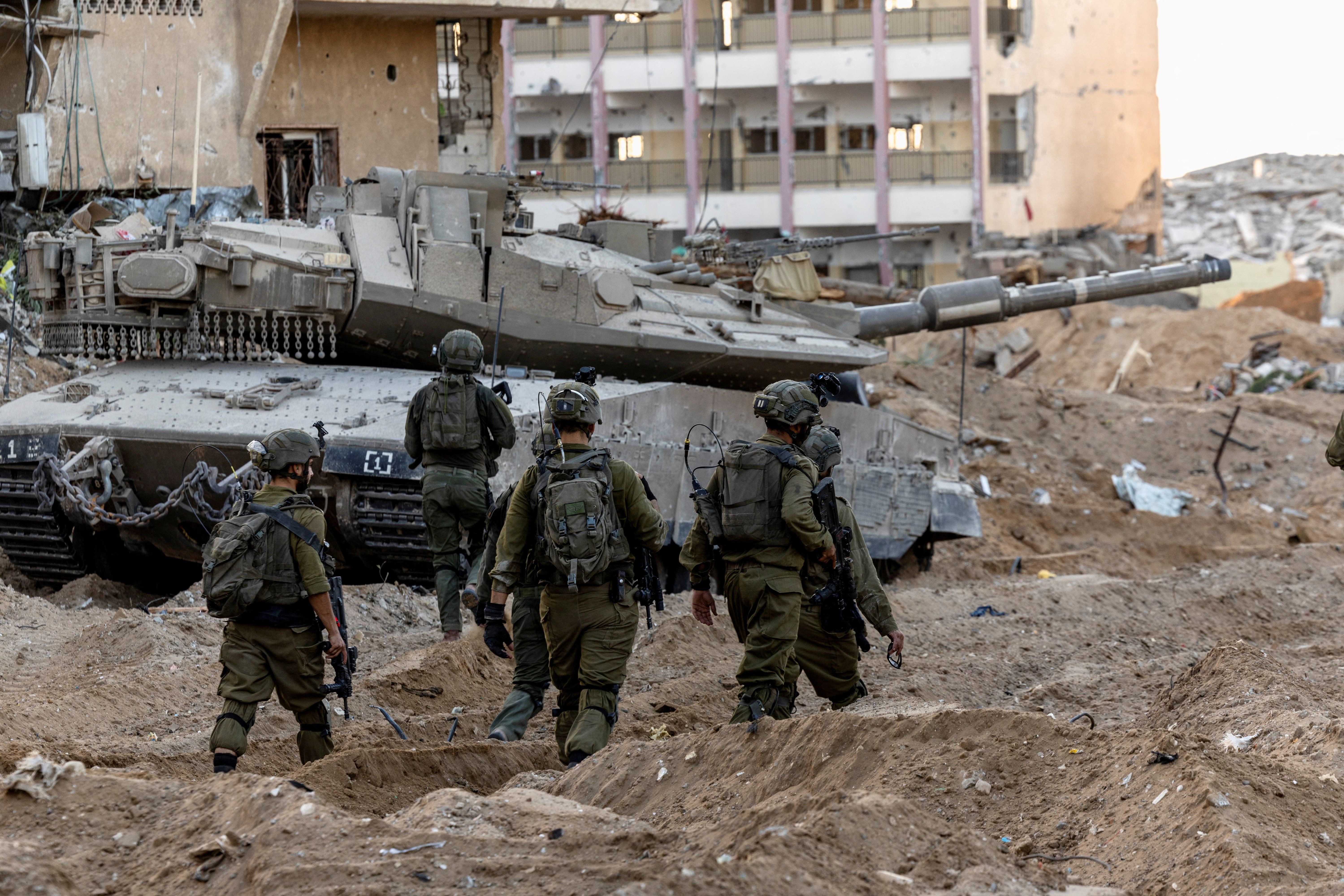 Israeli soldiers walk through rubble, amid the ongoing ground invasion against Palestinian Islamist group Hamas in the northern Gaza Strip, November 8, 2023.