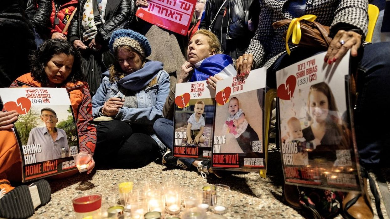 Israelis sit together as they light candles and hold posters with the images Oded Lifschitz, Shiri Bibas, and her two children, Kfir and Ariel Bibas, seized during the deadly Oct. 7, 2023 attack by Hamas, on the day the bodies of the deceased hostages were handed over under by Hamas on Feb. 20, 2025.