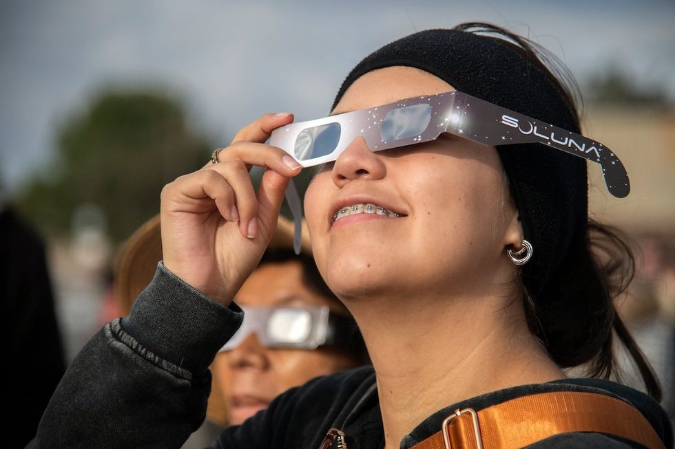 Laura Luciano of Stockton looks at the solar eclipse looks through special glasses during a watch party held by the Delta College Physics-Math-Computer Sciences Club and the the Stockton Astronomical Society on the campus of San Joaquin Delta College in Stockton on Oct. 14, 2023. 