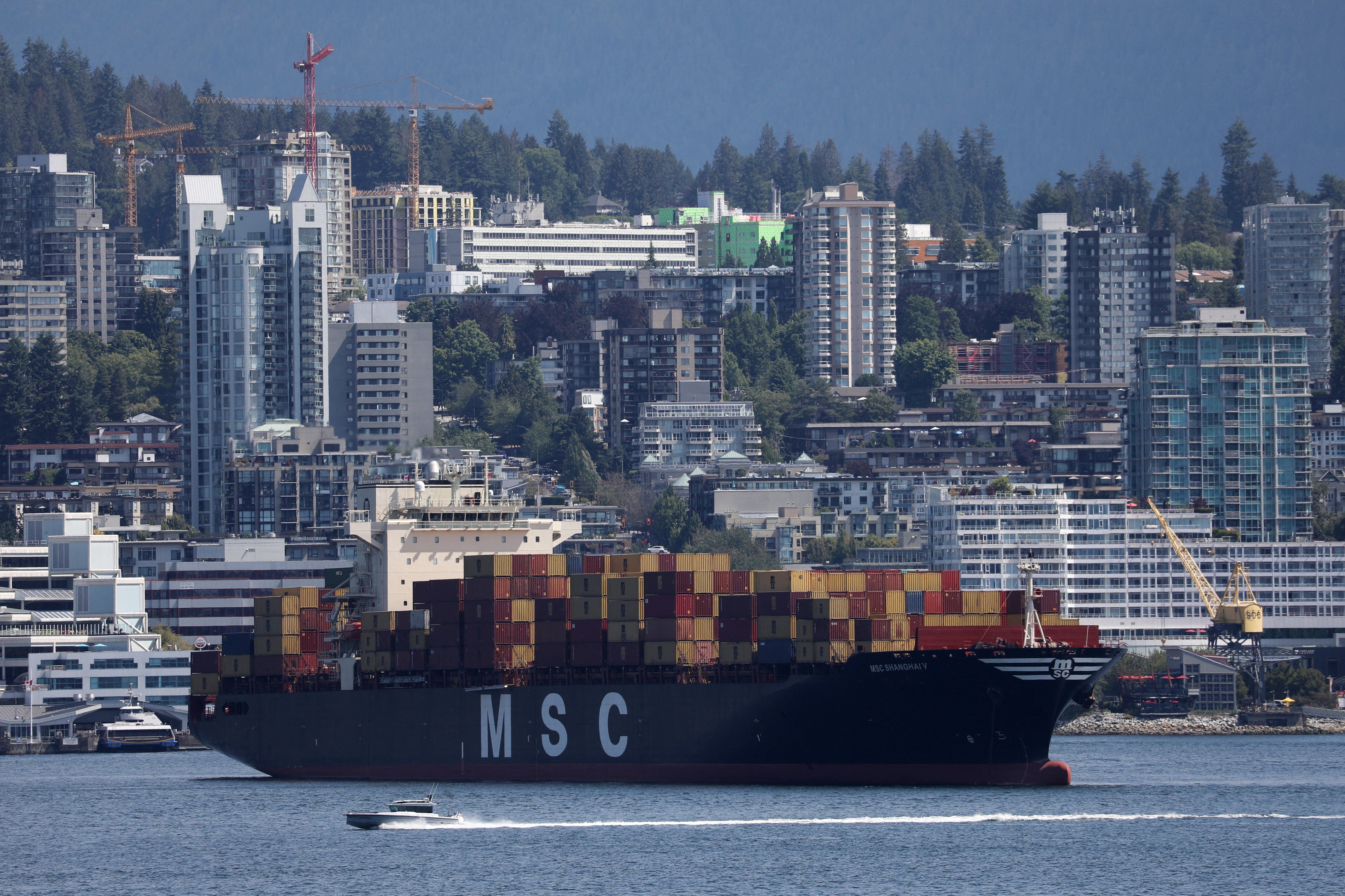 ​A boat passes a container ship at anchor during a strike by the International Longshore and Warehouse Union Canada at Canada's busiest port of Vancouver, British Columbia.